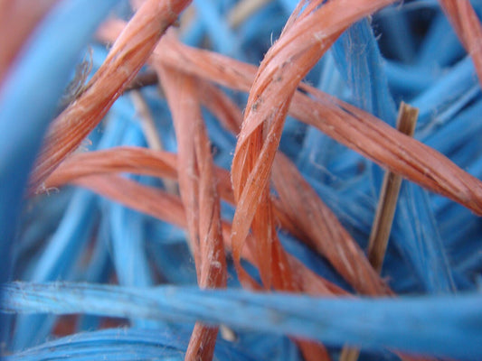 Close-up of blue and red polypropylene baler twine strands showing the fibrillated split-film texture