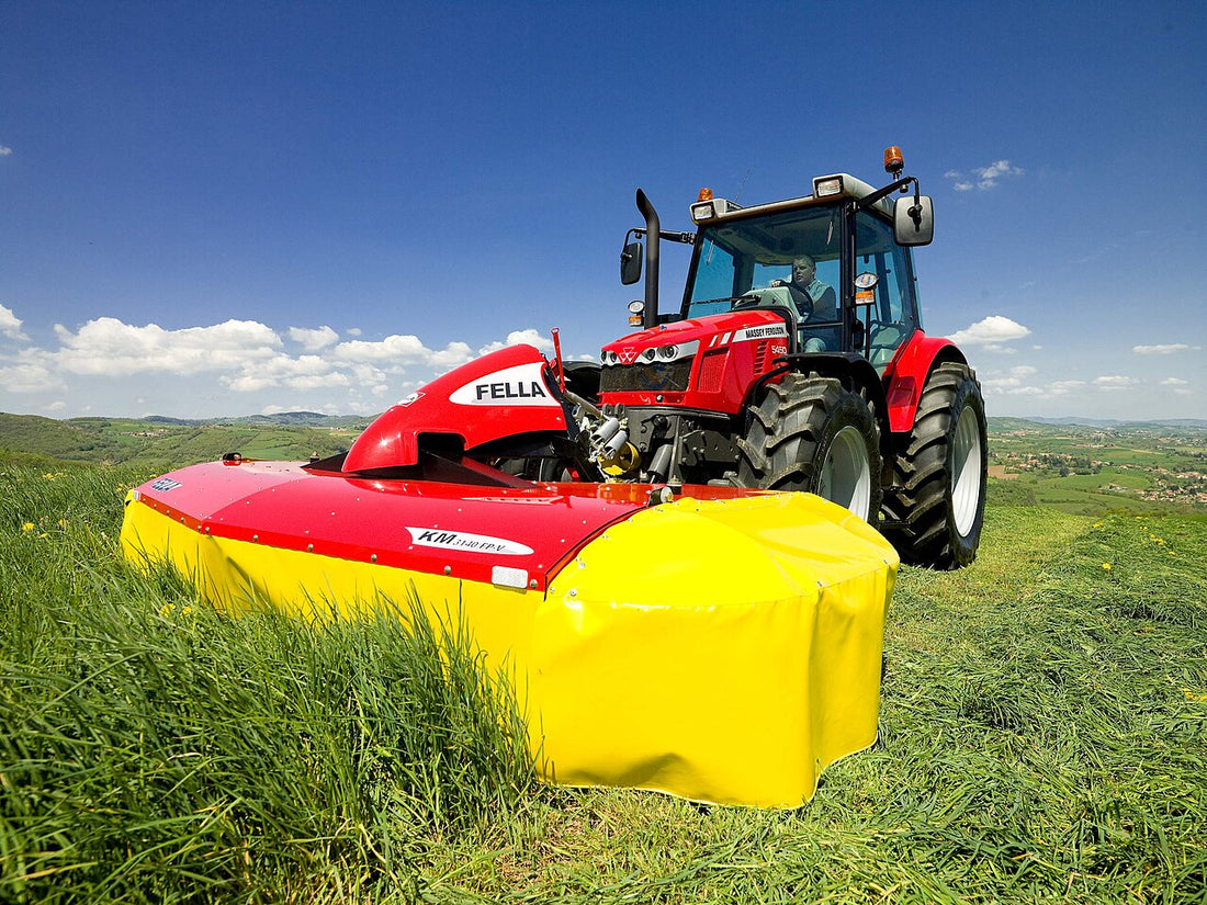 Red Fella KM 3140 FP-V two-drum mower with yellow drum covers mounted behind a Massey Ferguson 5450 tractor cutting green grass in a hillside hay field