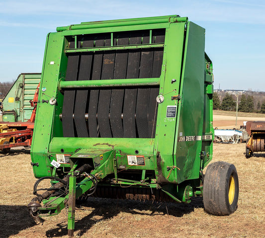 A John Deere 535 round baler parked in a farm lot