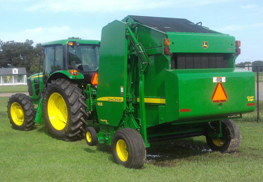 A round baler working in a hay field — round baler fires almost always start with a failed bearing igniting packed chaff, so watch bearing temps and keep the machine blown clean.