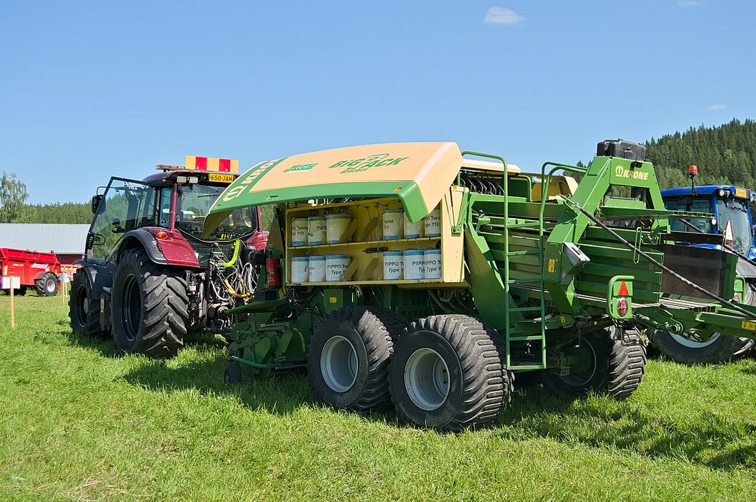 A Krone BiG Pack large square baler hitched behind a Valtra tractor in a hayfield, the kind of high-horsepower setup a 3x3 or 4x4 big square baler requires
