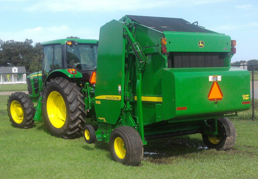 A John Deere 568 round baler with MegaWide Plus pickup and Cover-Edge net wrap hitched to a tractor