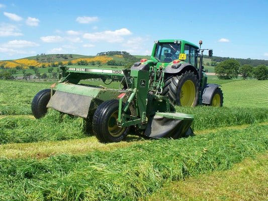 Tractor pulling a mower-conditioner through a grass field, laying the cut crop into a swath behind the machine