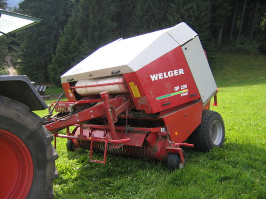 Rear of a Welger RP 220 Profi round baler with the net box open showing a white net wrap roll seated in its cradle