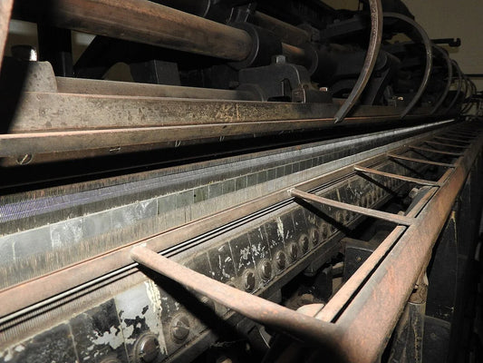 Warp knitting machine on a textile factory floor — the same machine class used to knit HDPE bale net wrap.