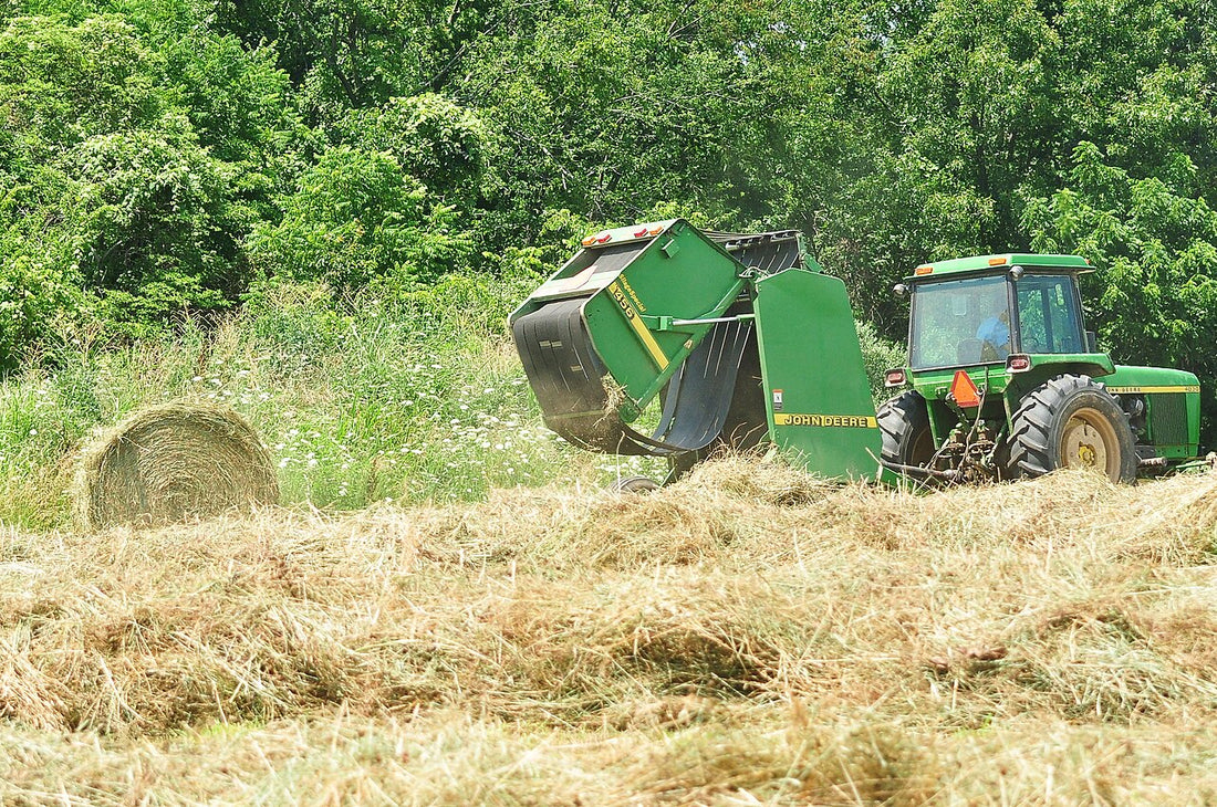A John Deere round baler making a hay bale in a southern Illinois field, in the same Roll-Belt lineage as the modern John Deere 460R