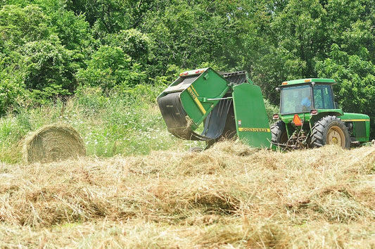 A John Deere round baler making a hay bale in a southern Illinois field, in the same Roll-Belt lineage as the modern John Deere 460R