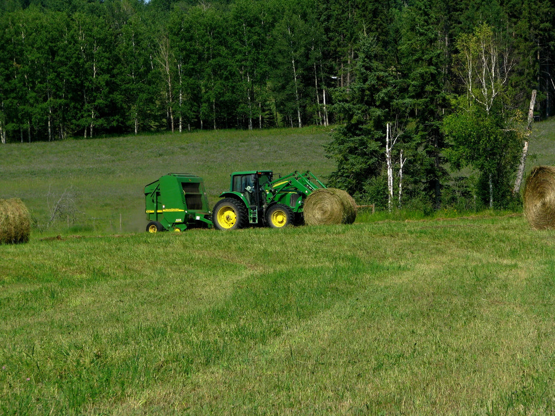 John Deere 5-foot round baler producing a 64-inch wrapped bale in a hayfield