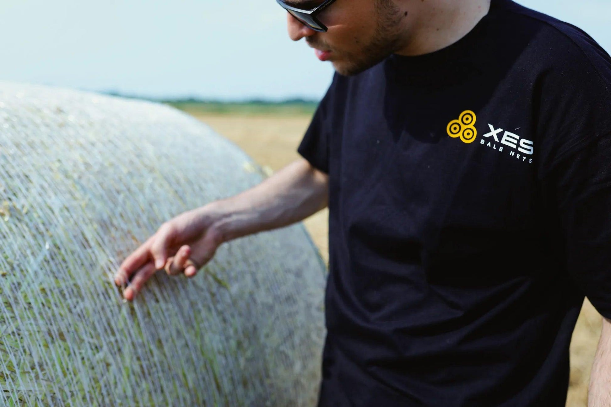 someone stands in front of a net wrap bale